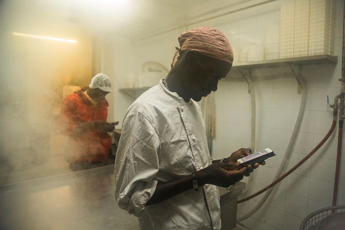 Cheikh Diop in the foreground and Ismael pass time as they wait for the recycled jars to sterilize with steam.  Making yogurt can take up to 10 hours.