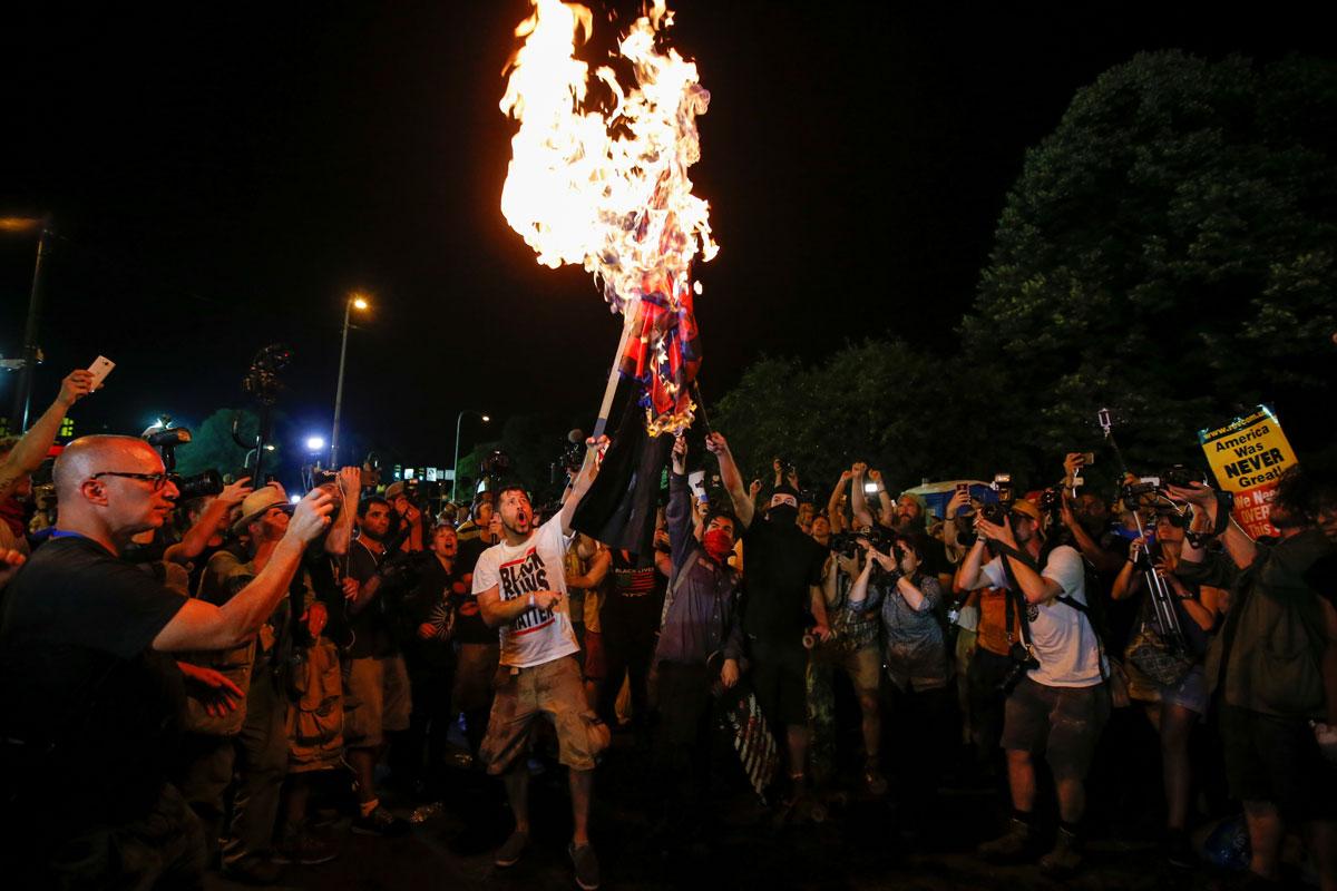 Protesters from various organizations surround men who were burning a modified American flag along the perimeter walls of the DNC in Philadelphia.