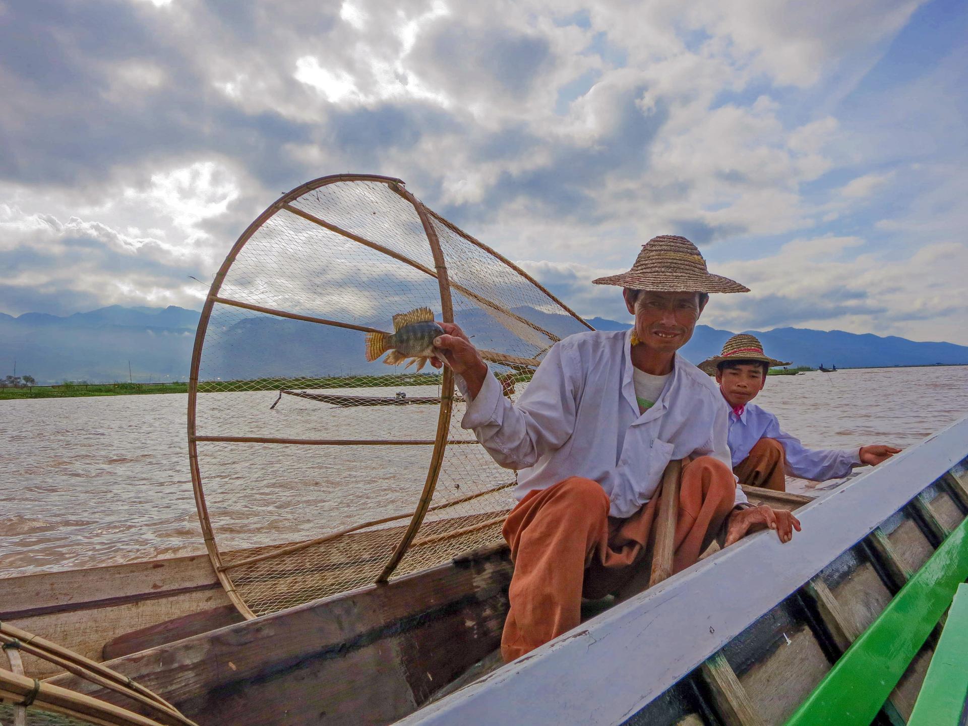 A fisherman holds up the already-dead fish that he used in his performance for tourists. With pollution and other human impacts harming Inle's aquatic ecosystem, the man now makes much more money performing his fishing routine than actually fishing.