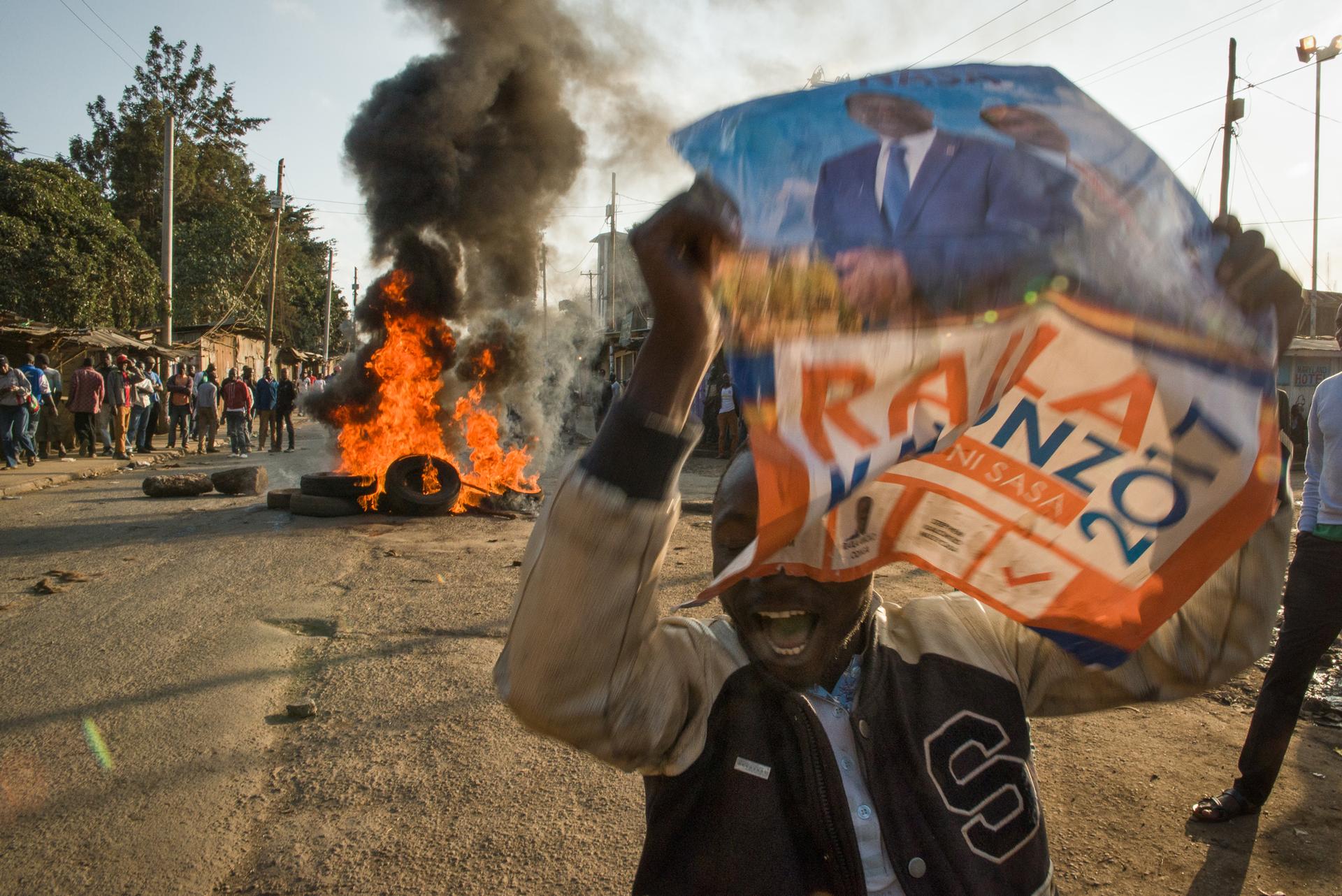 A man holds a campaign sign for presidential candidate Raila Odinga of the opposition party in the Kibera neighborhood of Nairobi, Kenya. Protesters were demanding that current President Uhuru Kenyatta concede to presidential candidate Raila Odinga of the
