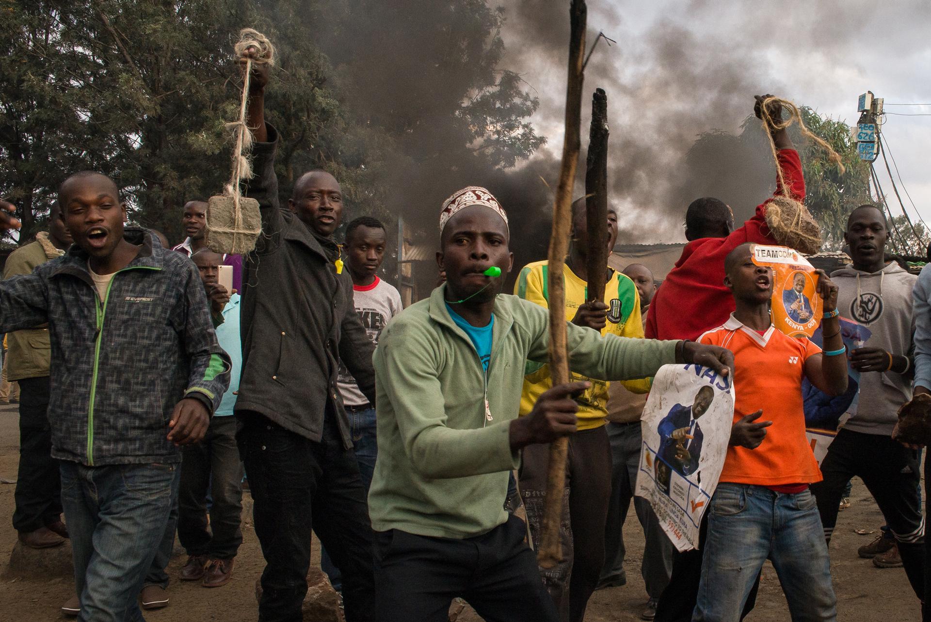 Men arm themselves with stones and clubs before clashing with residents in Kibera, an informal settlement in Nairobi, Kenya. The men supported presidential candidate Raila Odinga of the National Super Alliance over current President Uhuru Kenyatta.