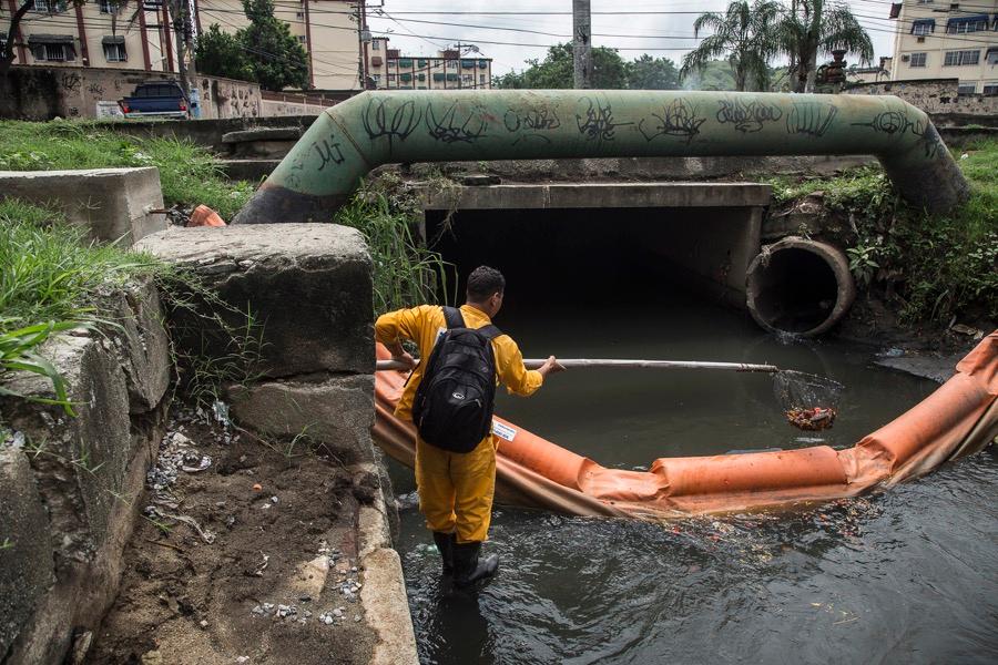 Marcelo Rocha, an employee of the Rio state environment institute, collects trash from a canal in the São Gonçalo neighborhood.