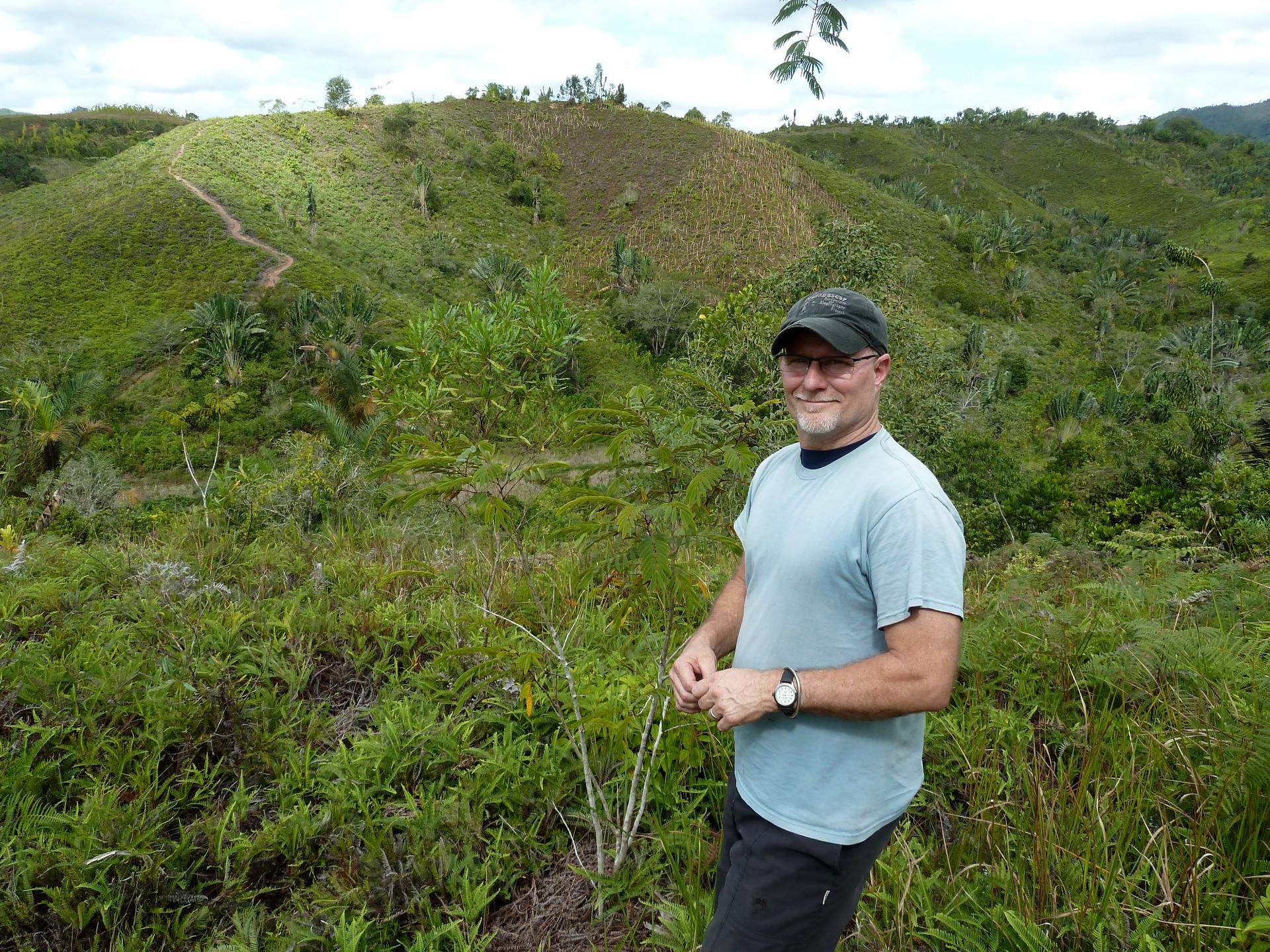 Madagascar Biodiversity Partnership director Ed Louis stands near a hillside recently replanted with new seedlings. The reforestation project depends on seeds eaten and pooped out by lemurs.