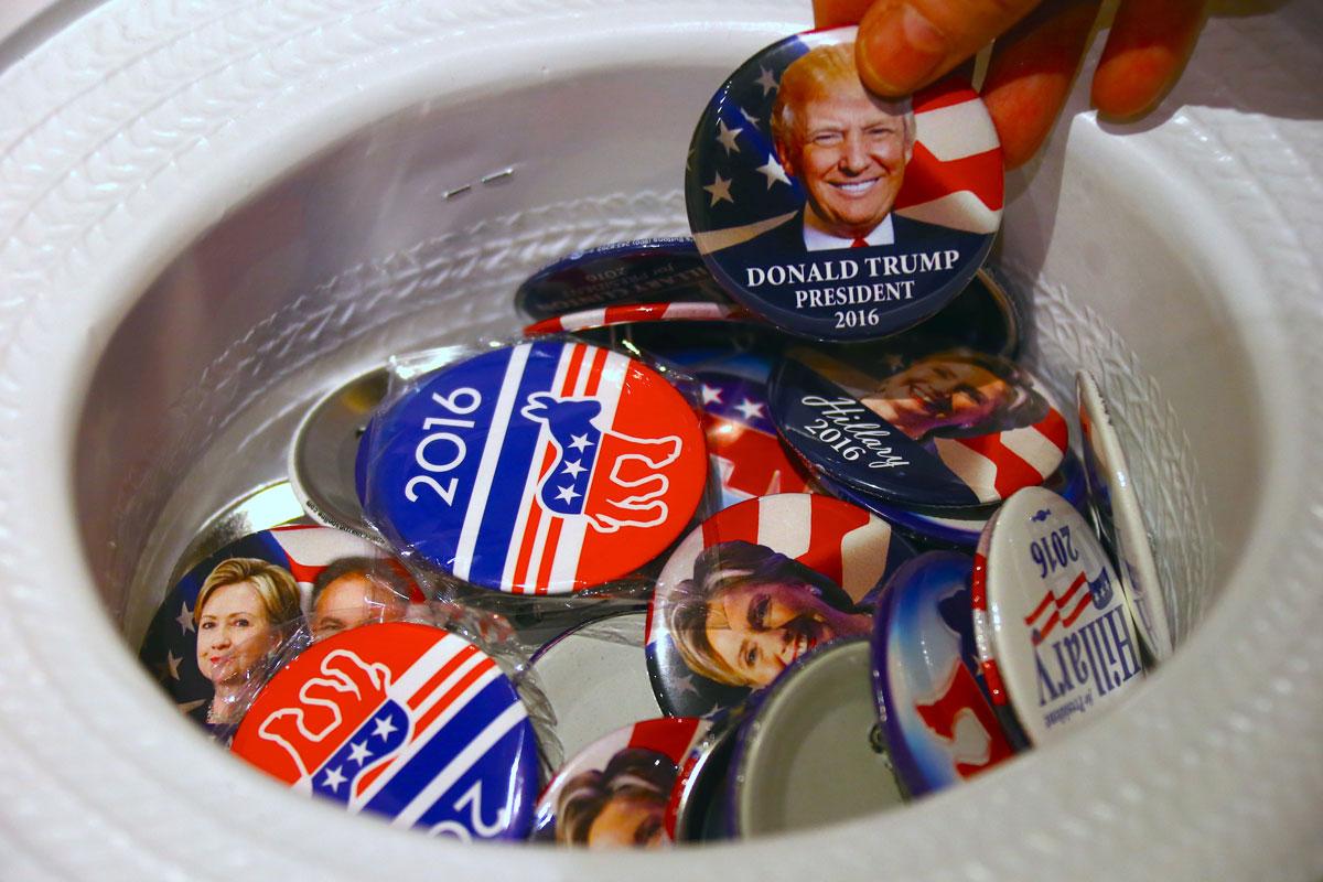 A guest at an event called the US Presidential Election Watch reaches for a badge from out of a hat displaying photographs of Republican candidate Donald Trump and Democratic candidate Hillary Clinton, in Sydney.