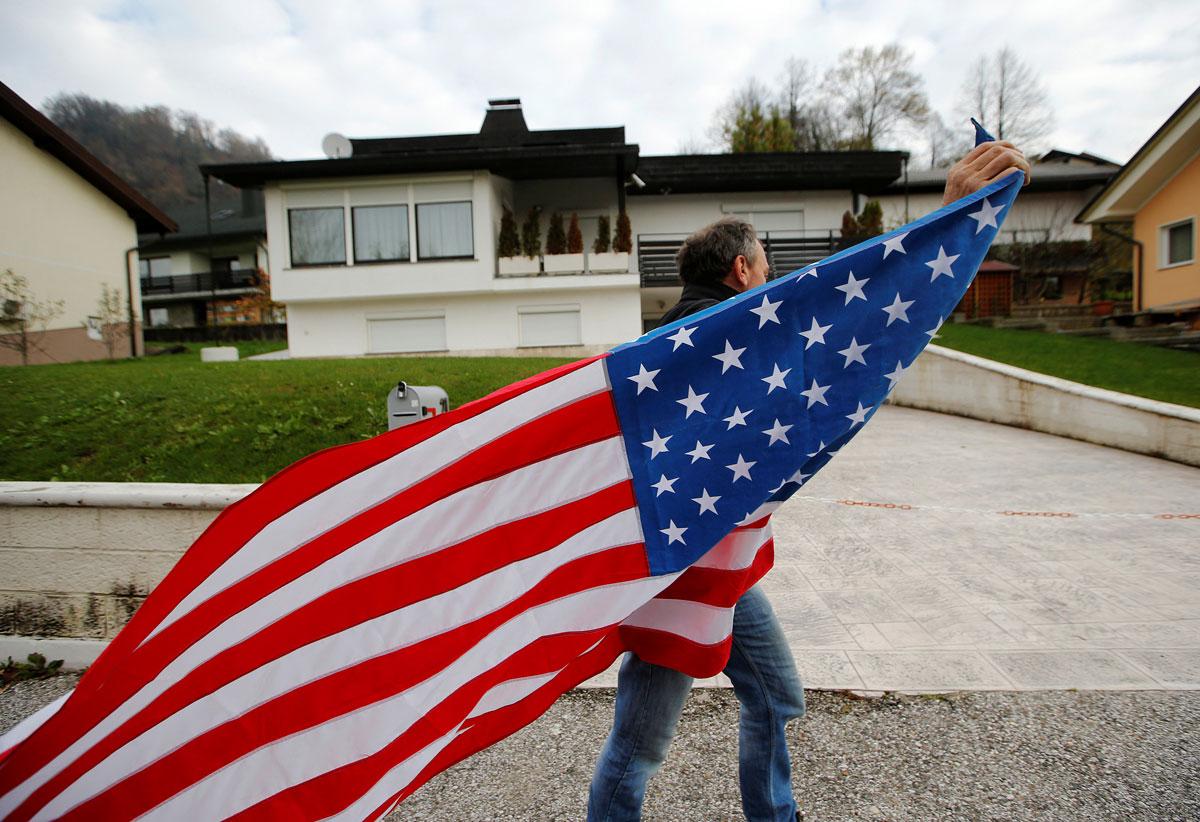 A man carrying the US flag is seen in front of Melania Trump parents' house during the election in Melania Trump's hometown of Sevnica, Slovenia.