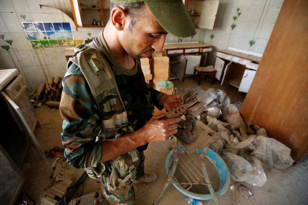 A member of the Shiite Badr Organization examines an item in a factory abandoned by Islamic State militants, following clashes in Fallujah.
