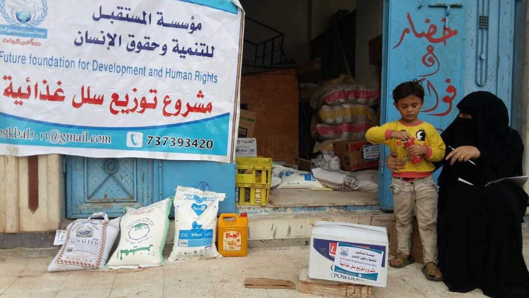 In Aden, Yemen, children stand outside the door to a warehouse beside bags of food readied for donation to the poor.