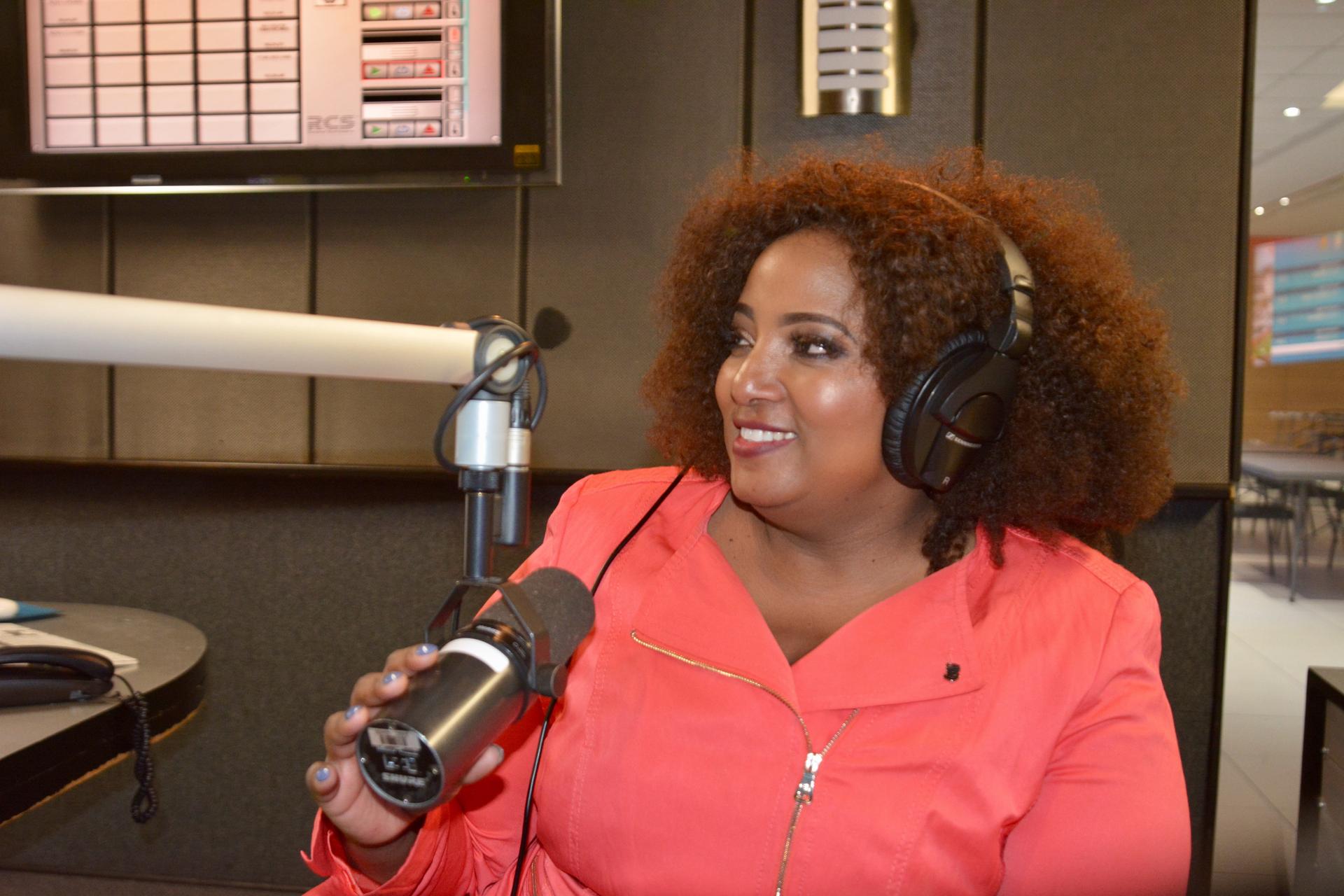 Sex talk radio host Criselda Kananda Dudumashe sitting in front of a microphone with headphones on.