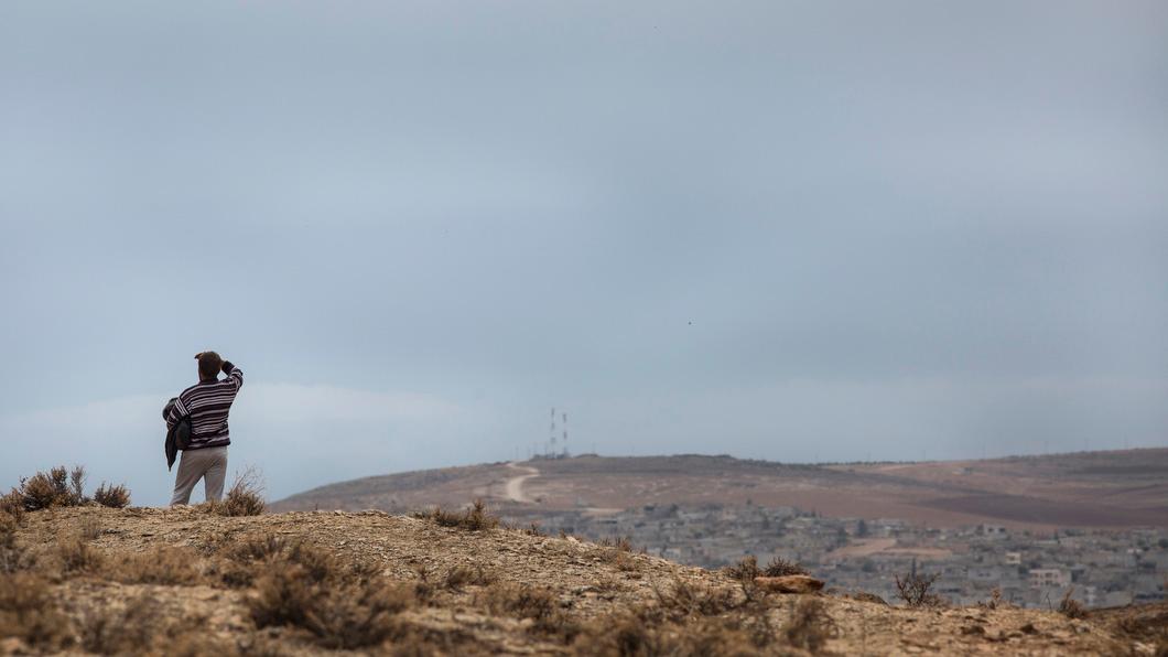 A man stands on a hill on the Turkish border from where people have been gathering to watch the fighting across the border in Kobane, Syria.