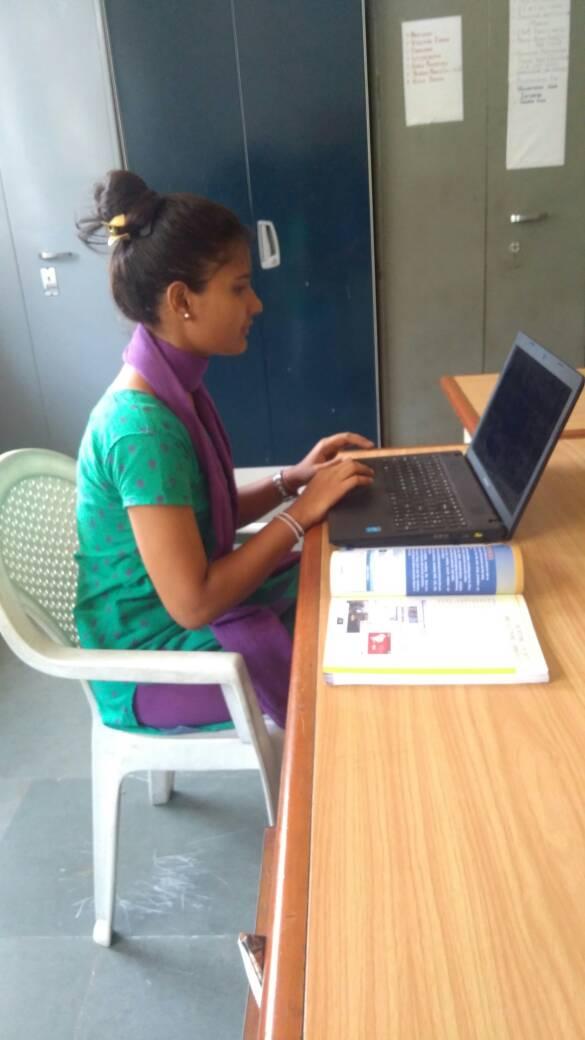 A young girl sits at a computer in India.