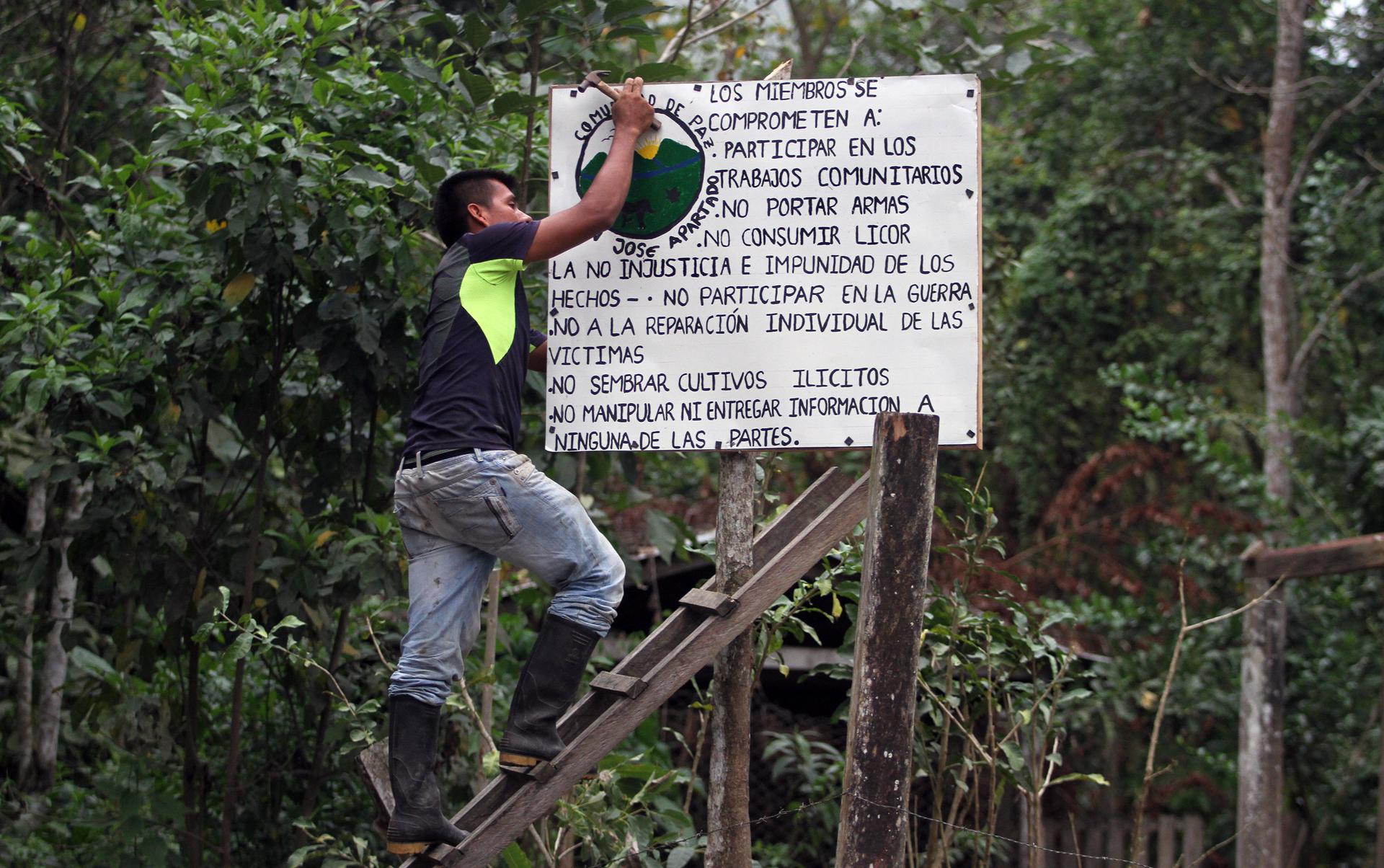 Germán, a community leader, hanging sign of community rules in preparation for 19th anniversary celebration