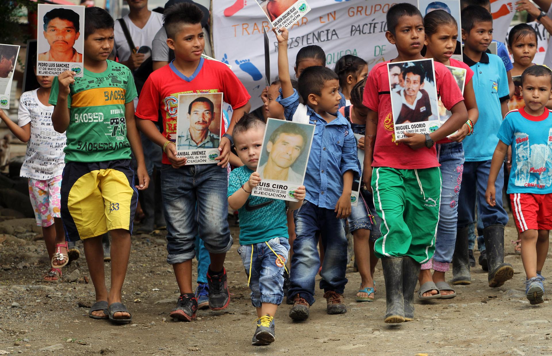 Kids carrying signs showing faces of massacred