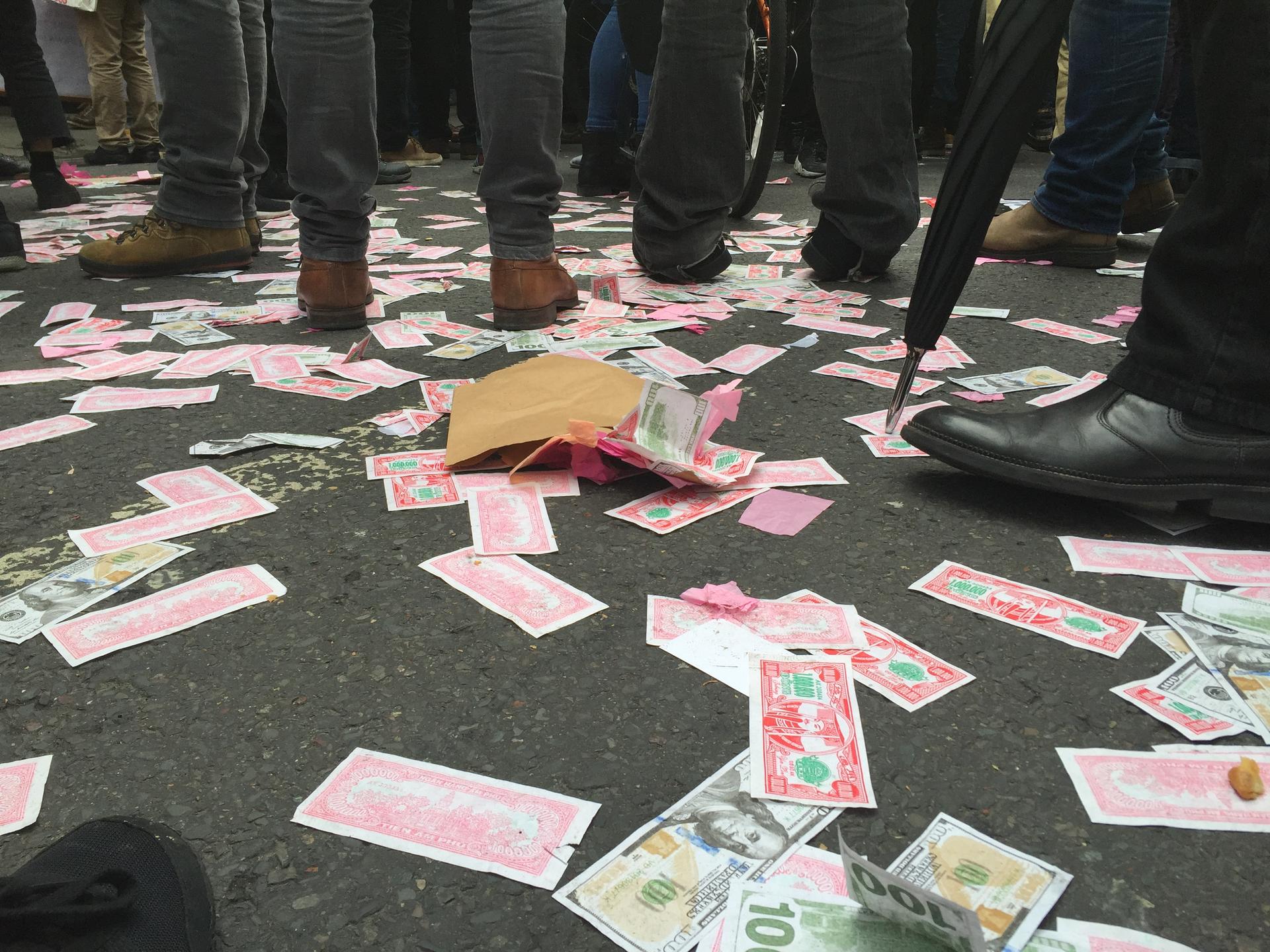Fake money covers the street in London where thousands called for the resignation of Prime Minister David Cameron.