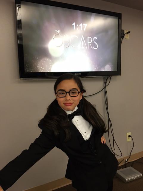 Estie Kung looks excited, with a screen of a countdown to her appearance on the Oscars behind her.