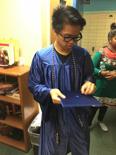 Young man in blue graduation gown, holding cap