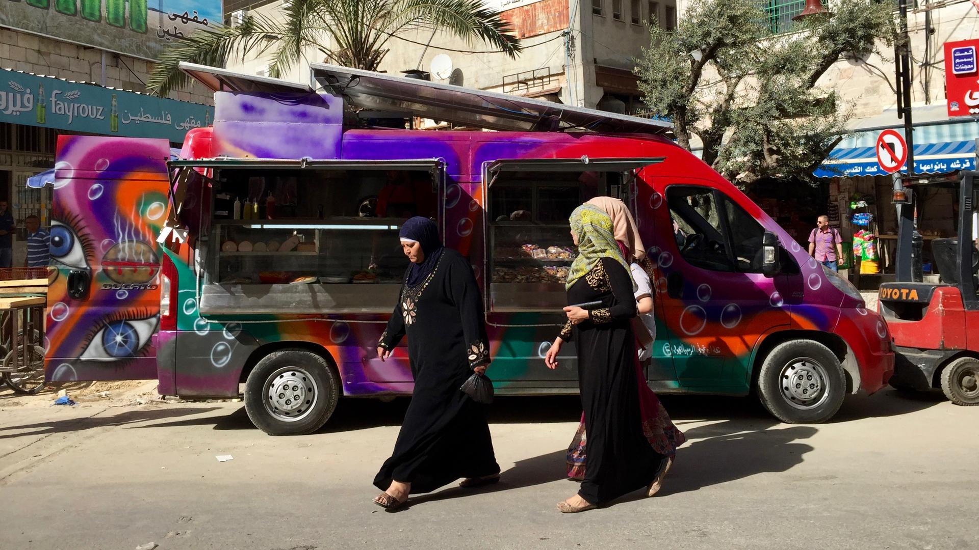 Palestinian women walk past 