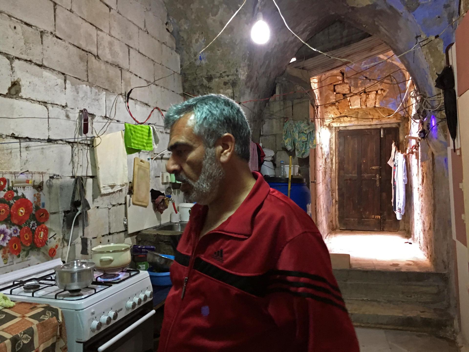 Jihad Al-Mohammed in his kitchen. He has a flat screen TV and a WiFi router where the synagogue used keep its Torah scrolls.