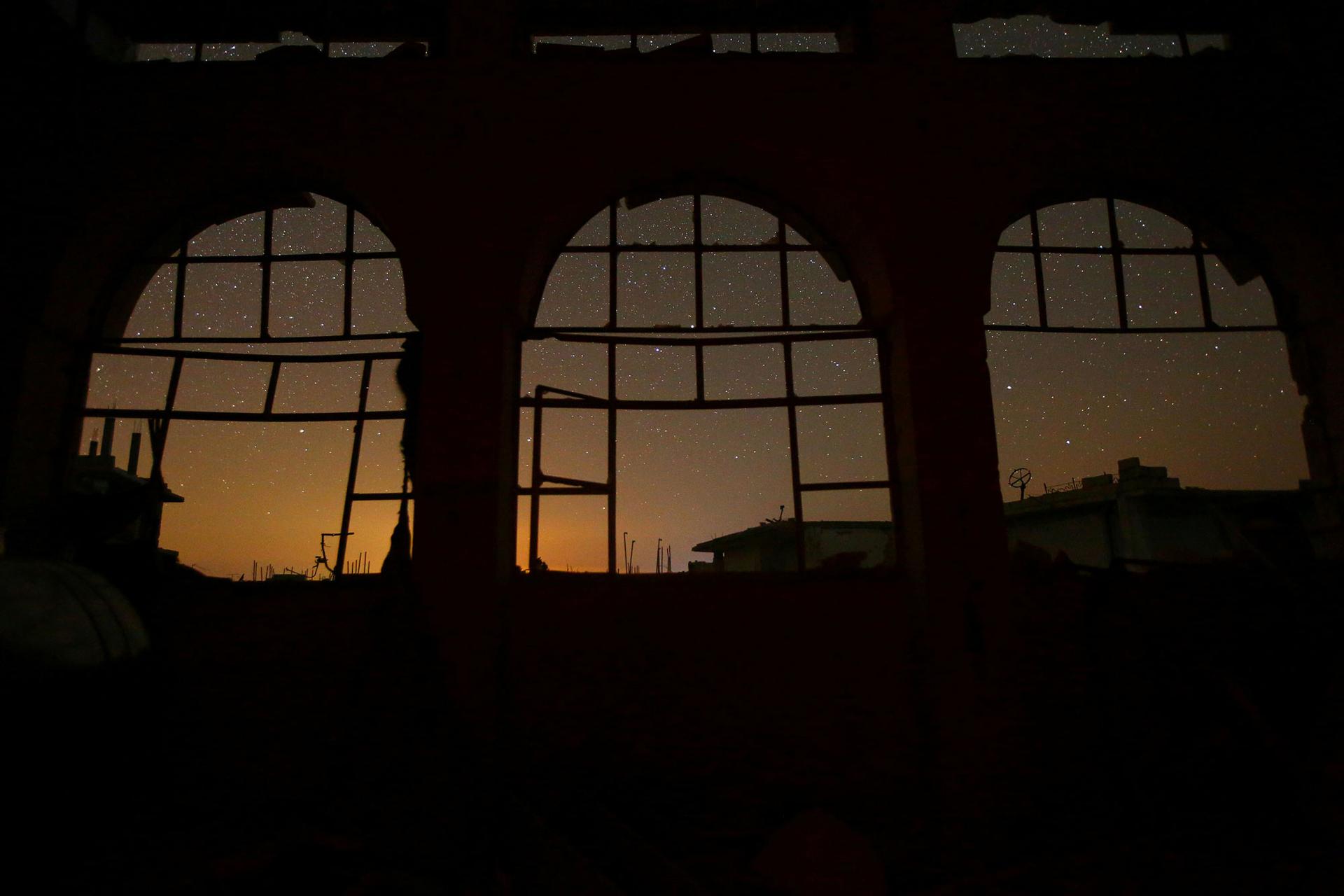 The night sky is seen through damaged windows in the rebel-controlled town of Binnish in Idlib province.