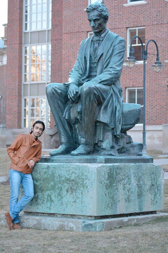 Karam Al Hamad posing with a statue of Abraham Lincoln at Syracuse University.