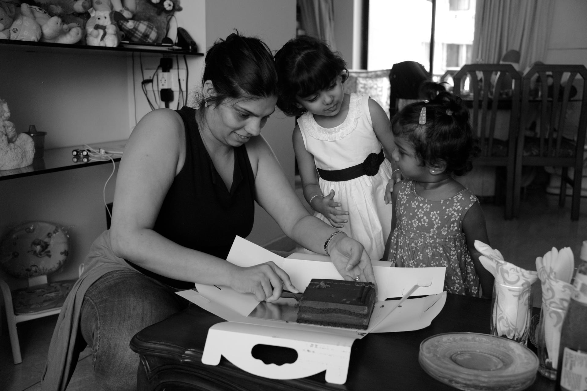 Ayesha D'Souza cuts some chocolate cake for her daughter and five-year-old friend Aliesha, also adopted.