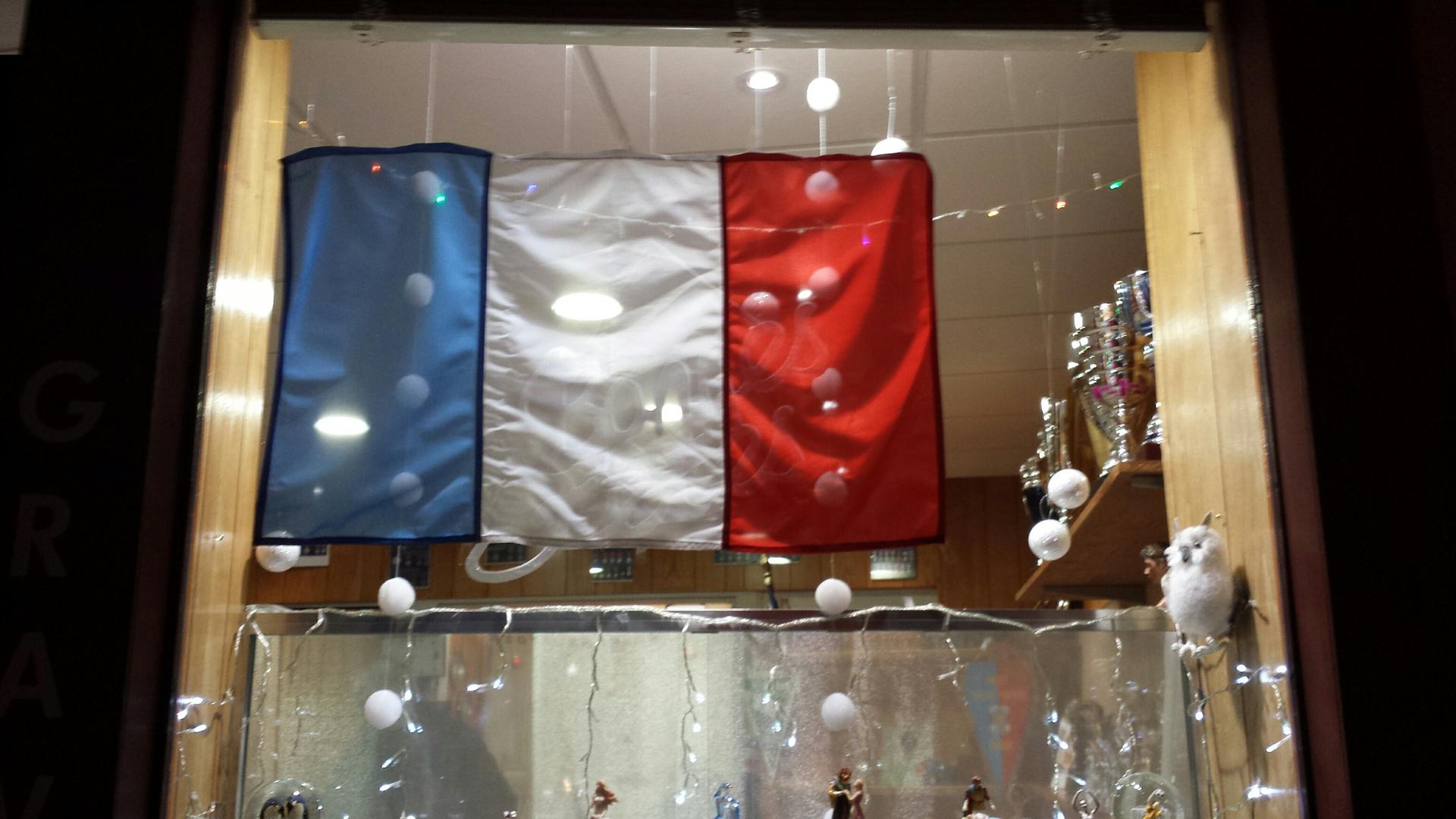 When Marie-Claude Augé ran out of French flags at her trophy shop, she cobbled together one for her shop window. The blue stripe here is from Luxembourg's flag.