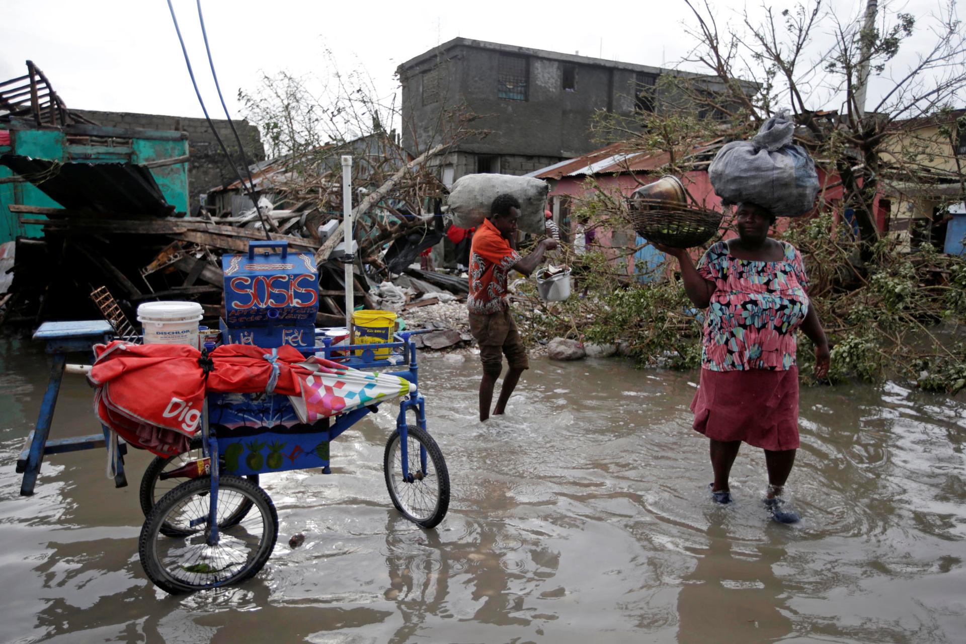 Residents amble through a flooded area after Hurricane Matthew in Les Cayes, Haiti.