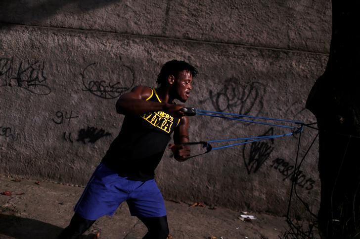 Popole Misenga, a judoka who will compete with a team of refugees during the 2016 olympics, trains with an elastic belt tied to a tree in front of a graffiti covered wall in Rio de Janeiro
