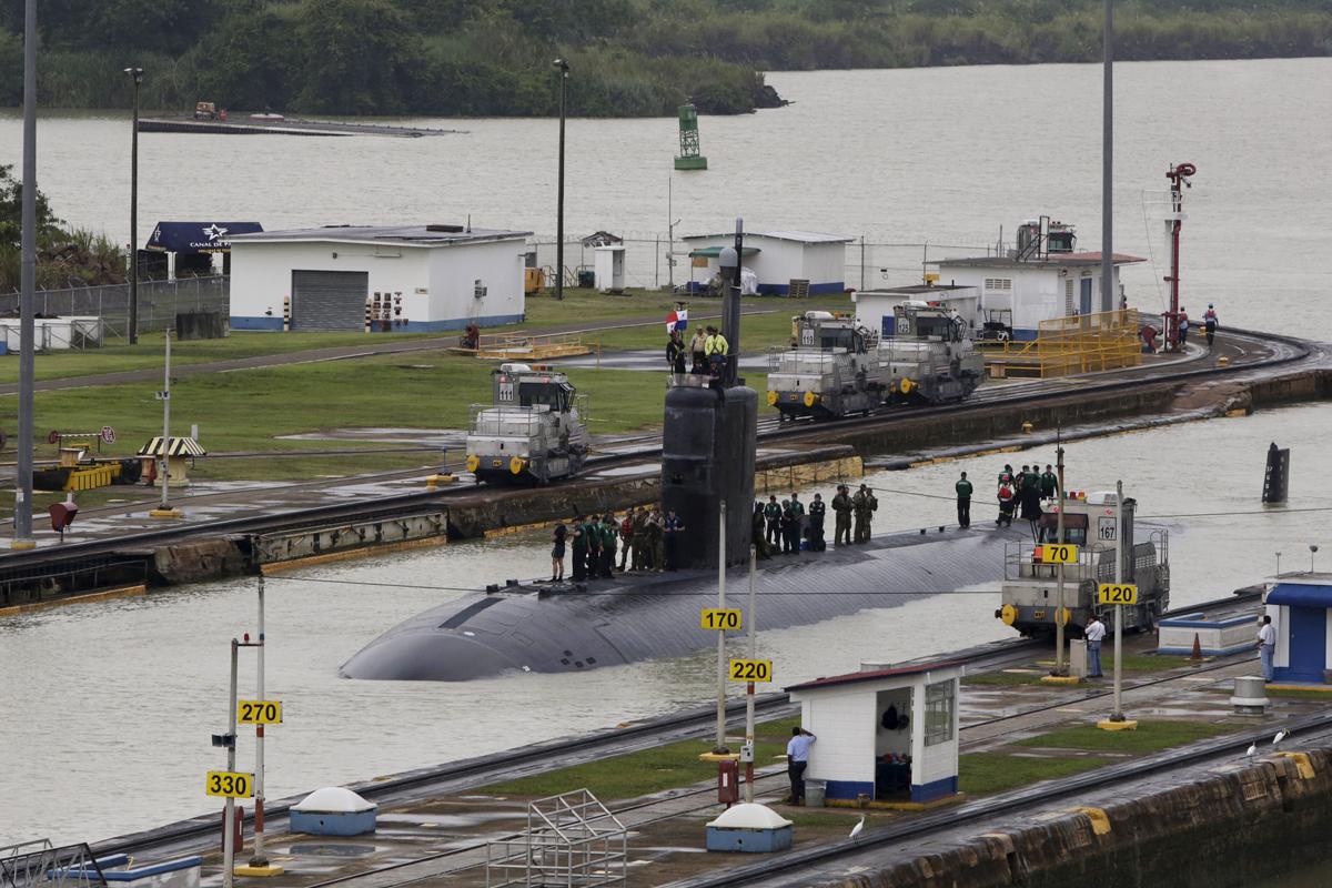 US Navy submarine USS Columbus is seen as it sails through the Miraflores locks at the Panama Canal. At present, electric 'mules' also keep vessels on track.