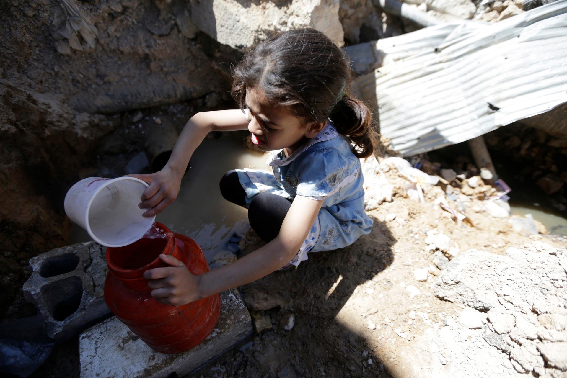 Aya, 8, fills containers with water obtained from a pool formed by damaged and leaking pipes in eastern Ghouta May 2, 2014.