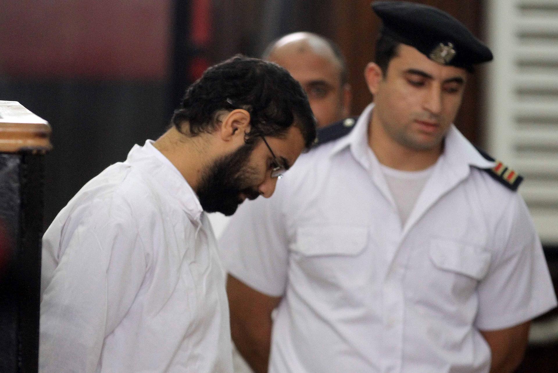 Activist Alaa Abdel Fattah stands in front of a police officer at a court during his trial in Cairo, November 11, 2014.
