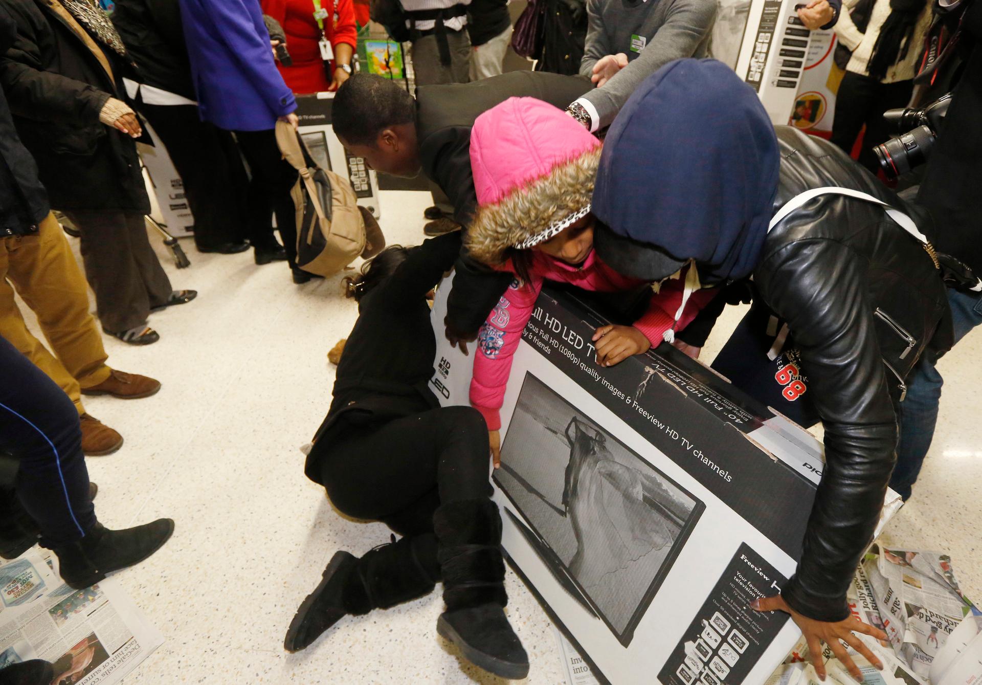 Shoppers wrestle over a television as they compete to purchase retail items on 