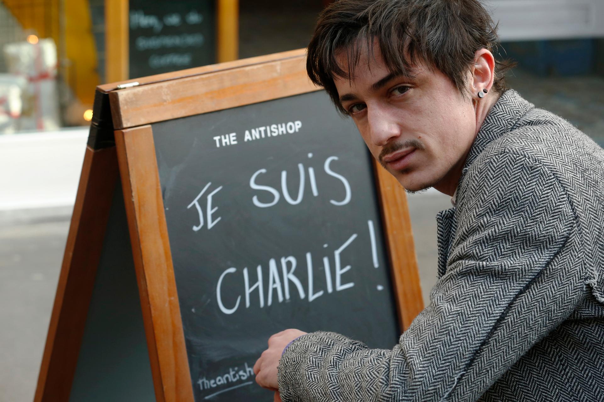 Adel Defilaux, a French-born Muslim, poses Wednesday outside his cafe in east London. Defilaux has received death threats for displaying the sign.