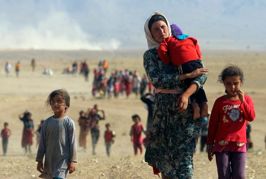 Displaced Yazidi people fleeing violence in Sinjar, walk toward the Syrian border on Aug. 11, 2014.