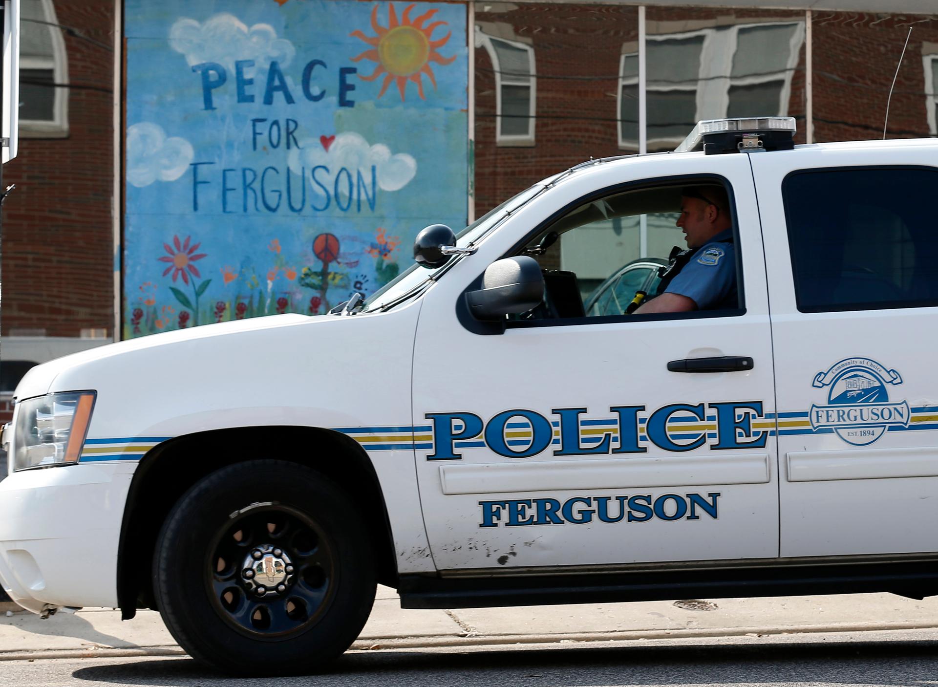 A Ferguson Police officer drives past a mural in Ferguson, Missouri, on March 12, 2015.