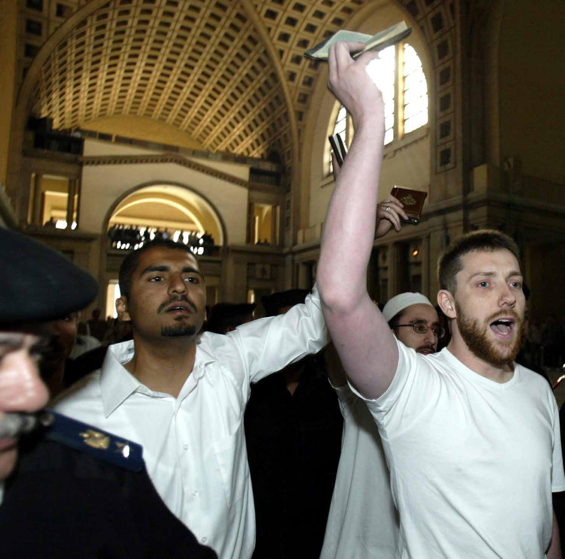 Maajid Nawaz (left) and fellow British citizen Ian Nisbet hold up copies of the holy Quran as they are led to court in Cairo, Egypt in March 2004. Nawaz and Nisbet were among a group of 26 people arrested in Egypt and sentenced to jail time for promoting