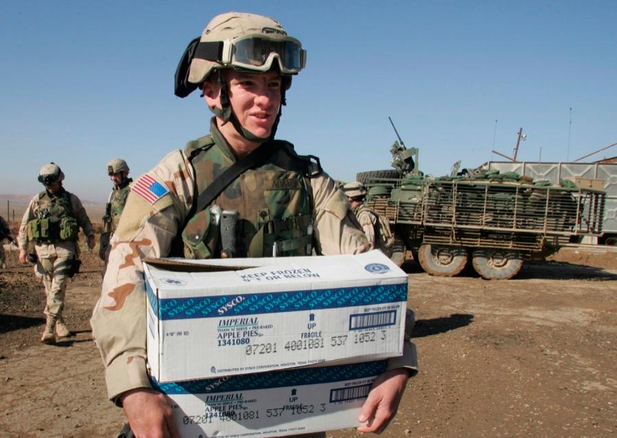 US Army medic Tony Adams arrives at a US military base near the town of Hamam al-Alil, Iraq, carrying two boxes of Thanksgiving pies for the troops on Nov. 25, 2004.