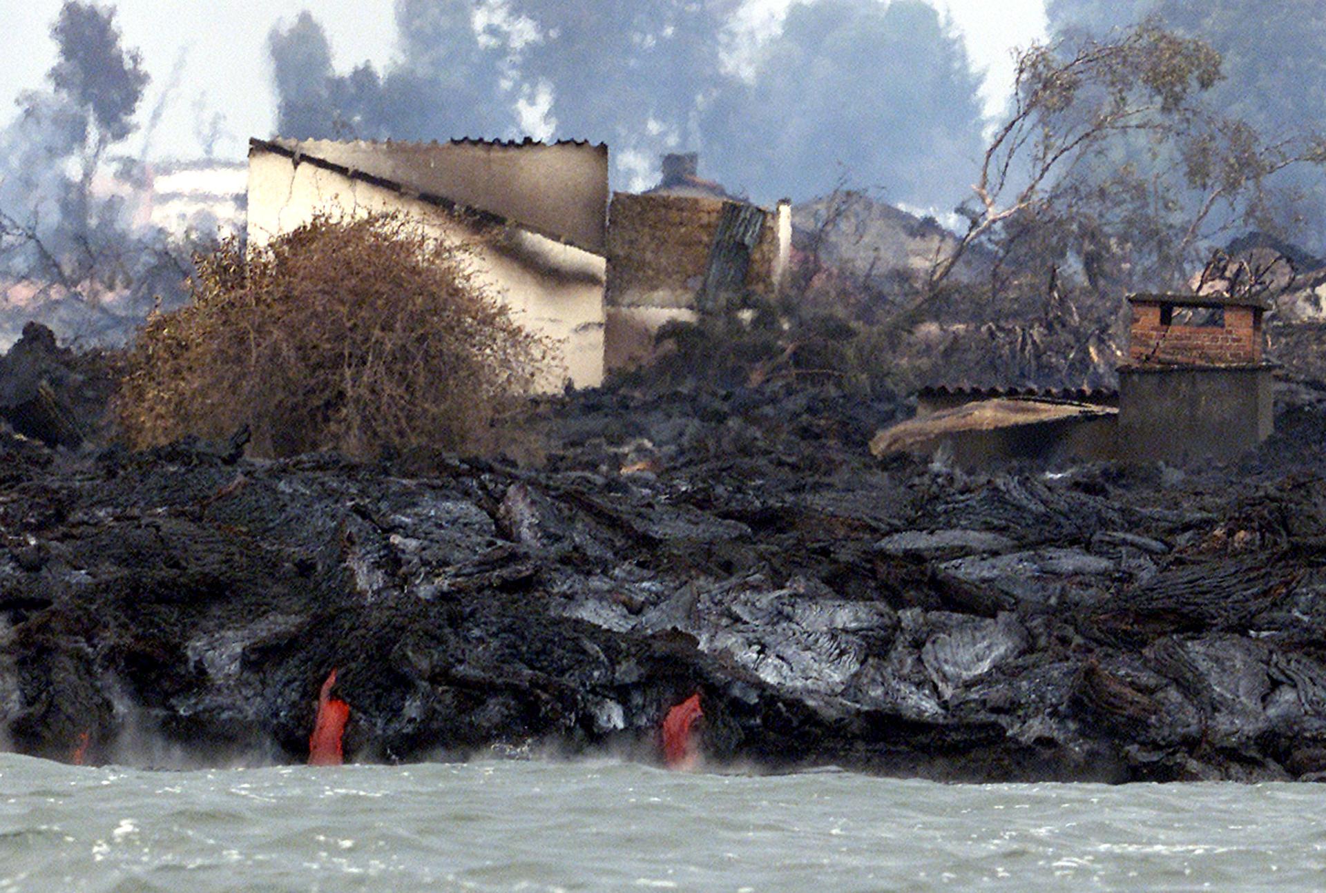Molten Lava pours into lake Kivu in front of burnt out houses in Goma January 21, 2002.