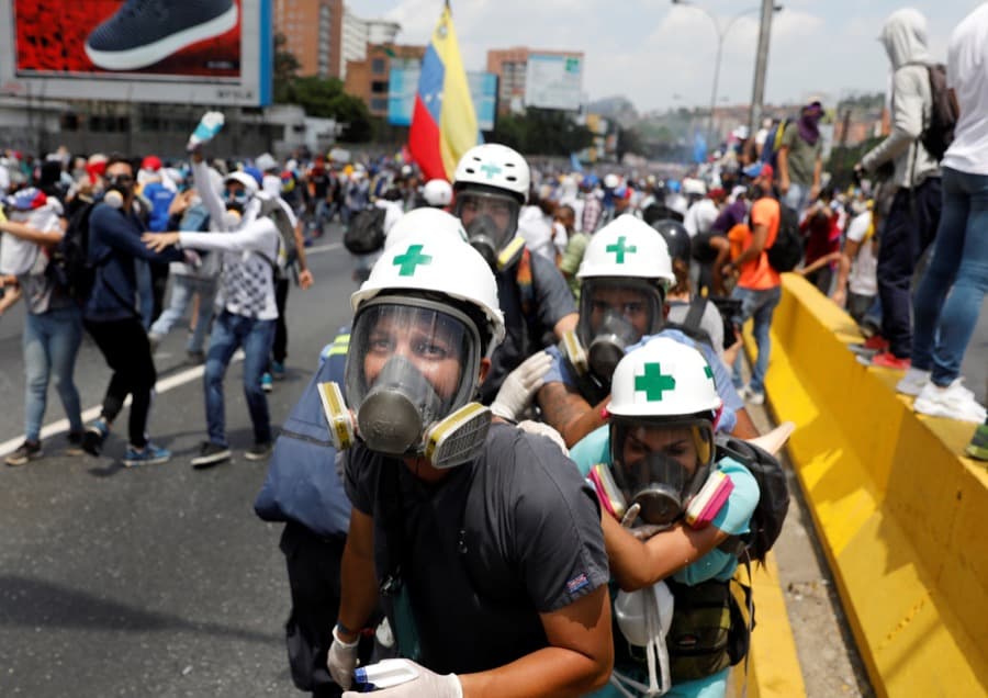 Volunteer members of a primary care response team huddle together during clashes with security forces at a rally against Venezuela's President Nicolas Maduro in Caracas, Venezuela