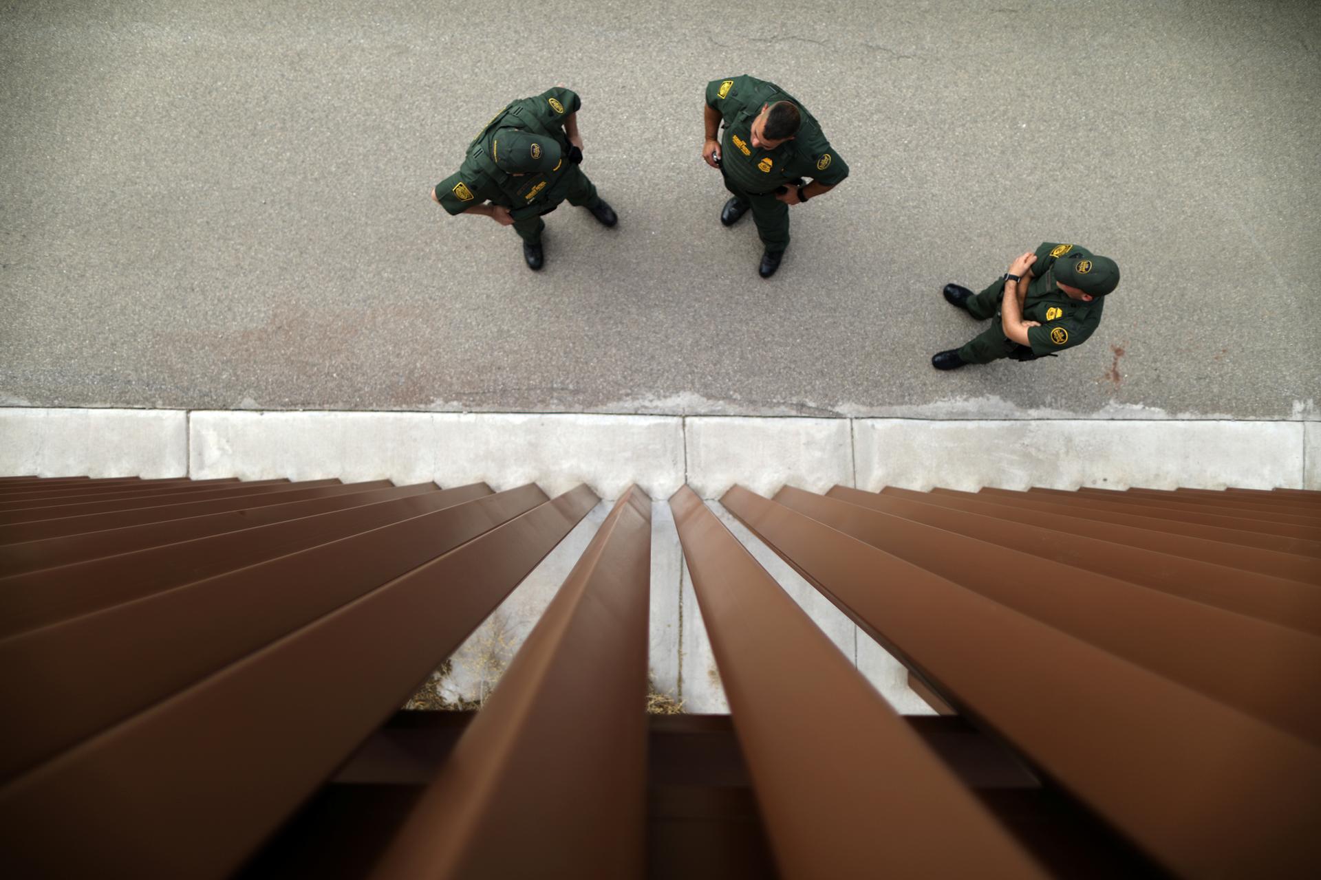 Border patrol agents stand next to a border fence used for training at the United States Border Patrol Academy in Artesia, New Mexico, June 8, 2017.