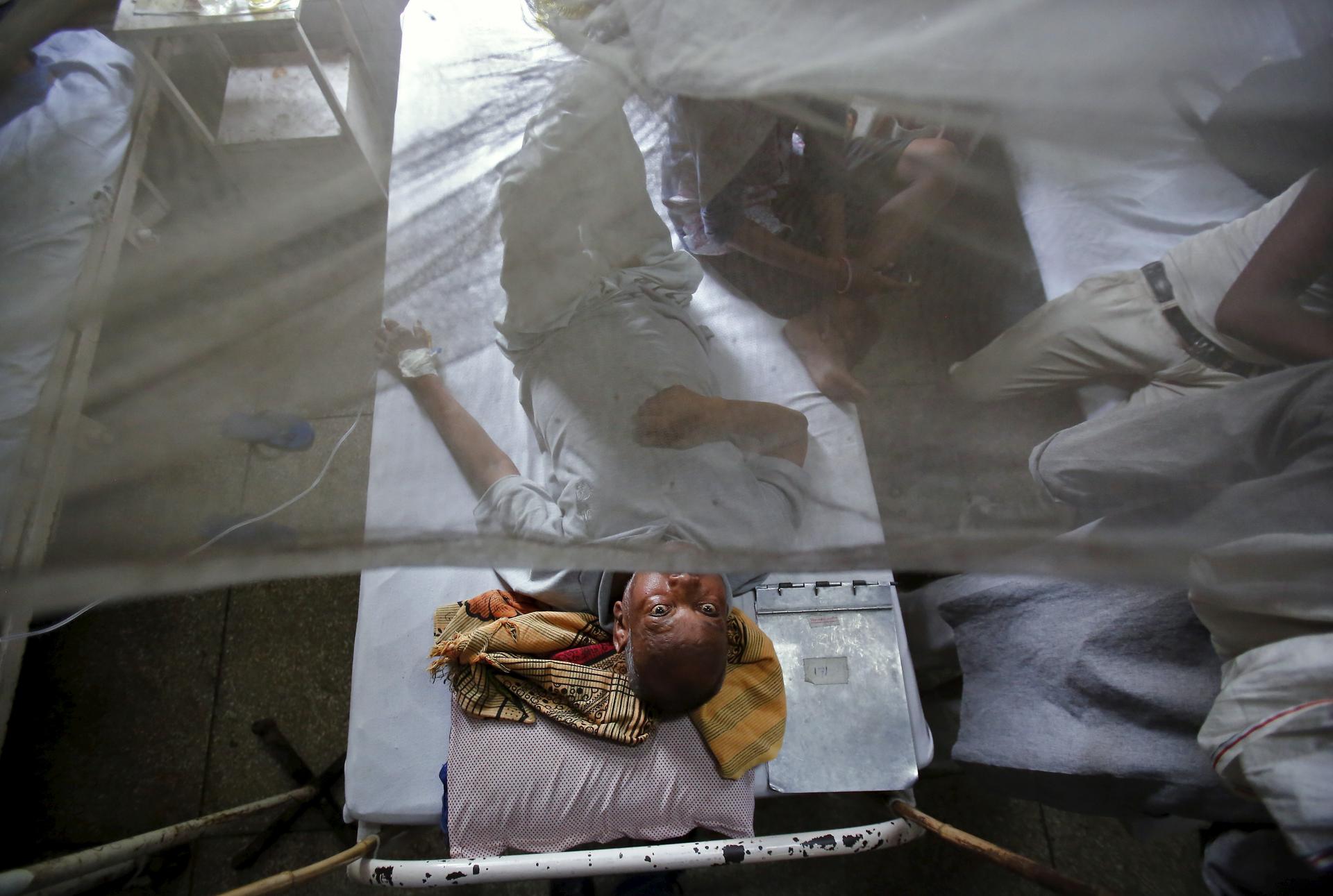 A patient awaits routine check-up as he lies under a mosquito net inside a dengue ward of a government hospital in New Delhi, India, September 18, 2015.