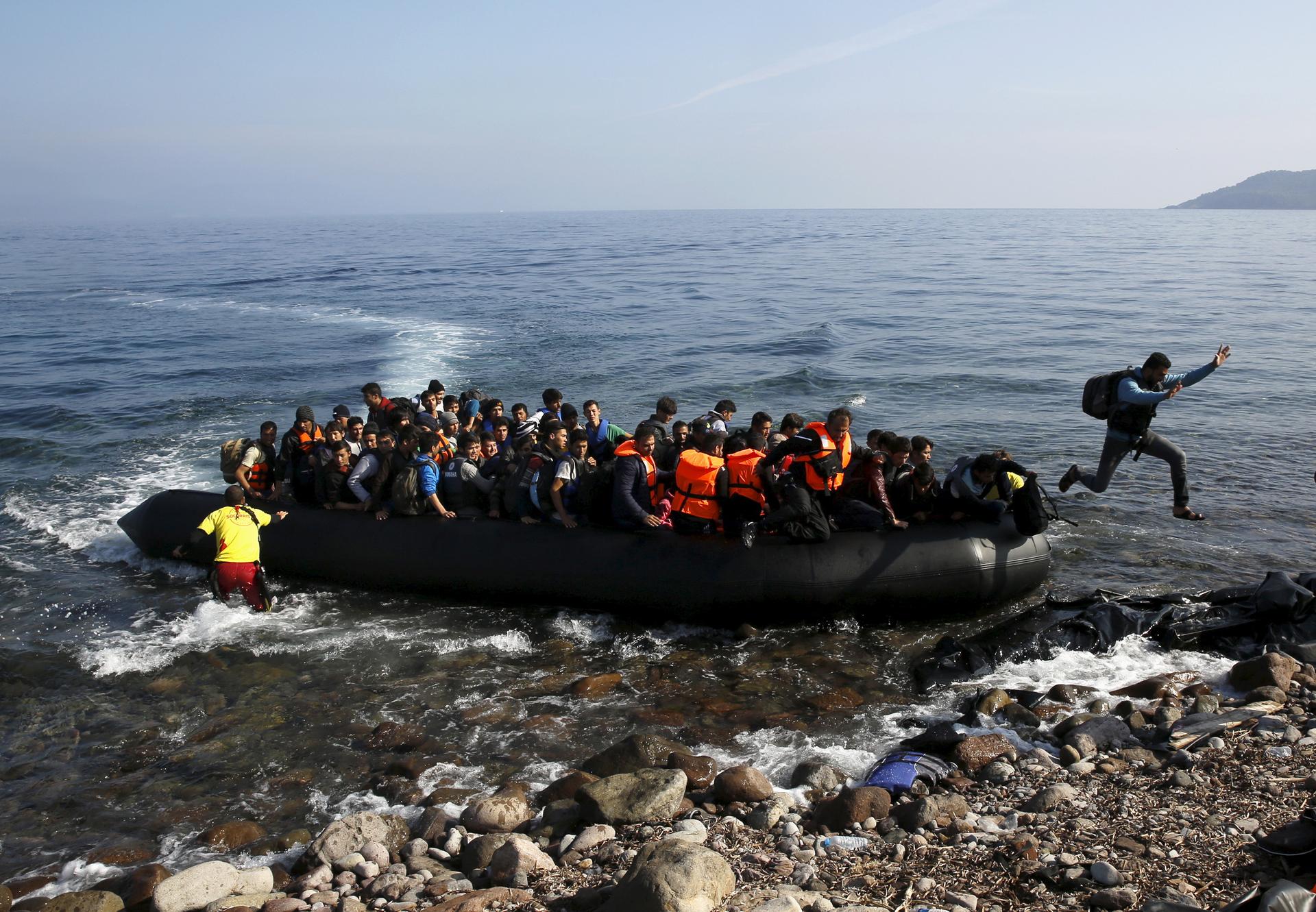 A migrant jumps off an overcrowded raft onto a beach on the Greek island of Lesbos, Oct. 19, 2015.