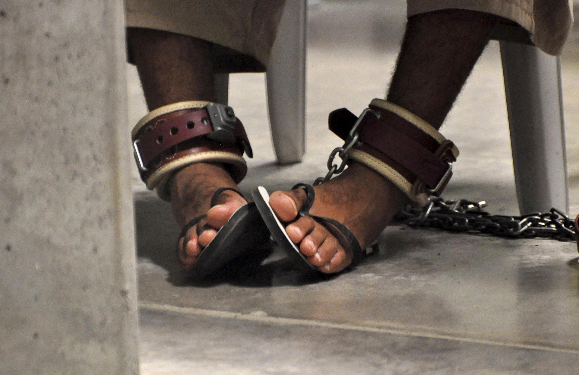 A Guantanamo detainee's feet are shackled to the floor as he attends a 