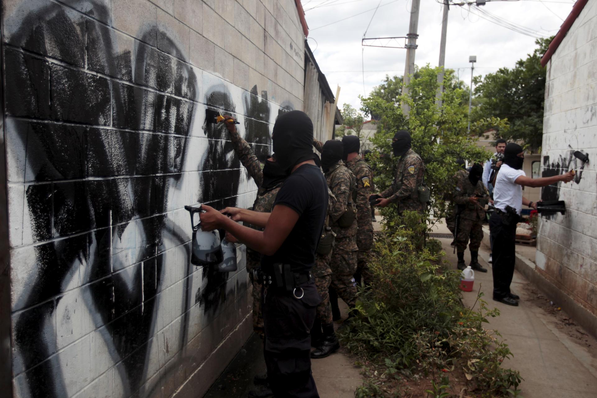 Soldiers and policemen paint over graffiti associated with the Mara Salvatrucha gang in El Rosal neighborhood in Quezaltepeque, El Salvador April 4, 2016.