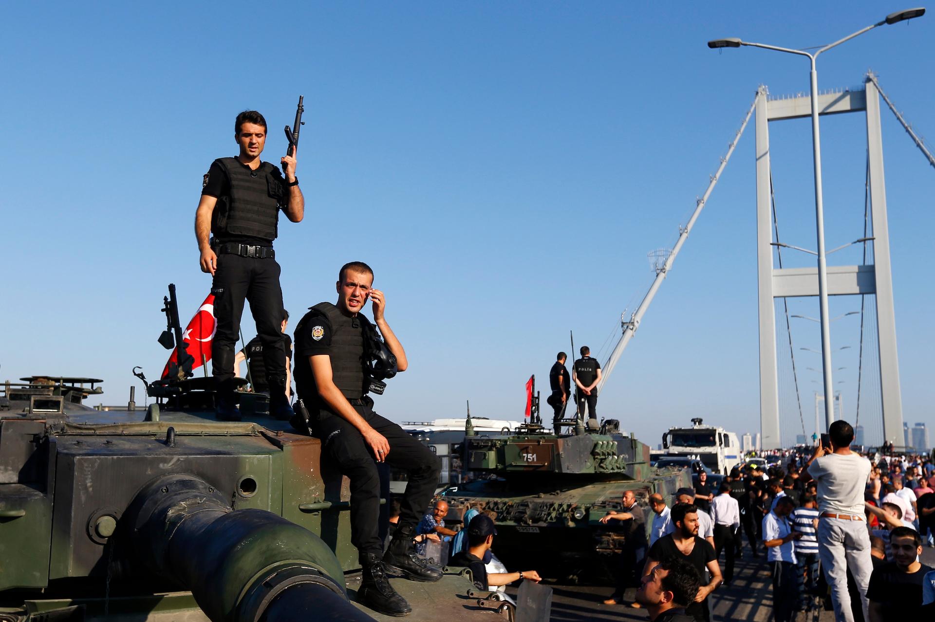 Policemen stand atop military armored vehicles after troops involved in the coup surrendered on the Bosphorus Bridge in Istanbul, Turkey, on July 16, 2016.
