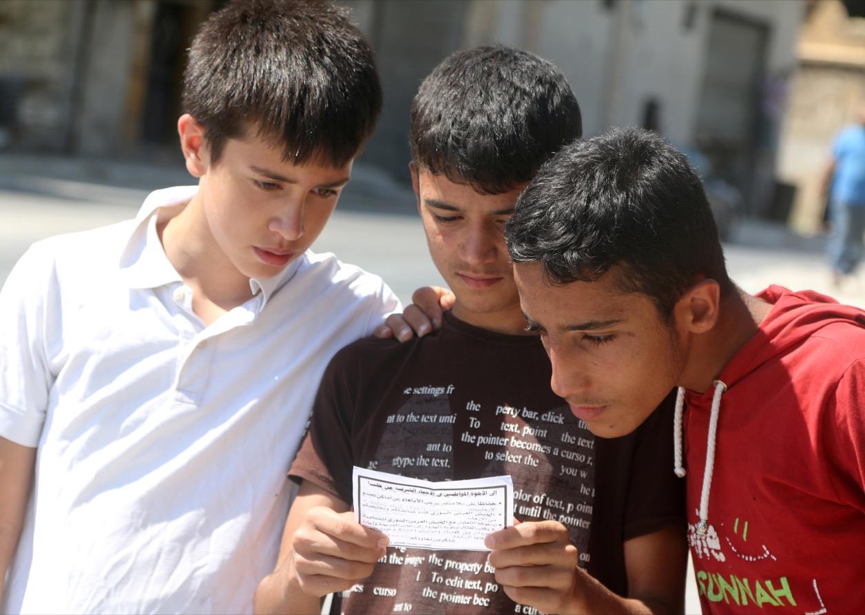 Boys read one of the informational leaflets dropped by the Syrian army over opposition-held Aleppo districts.