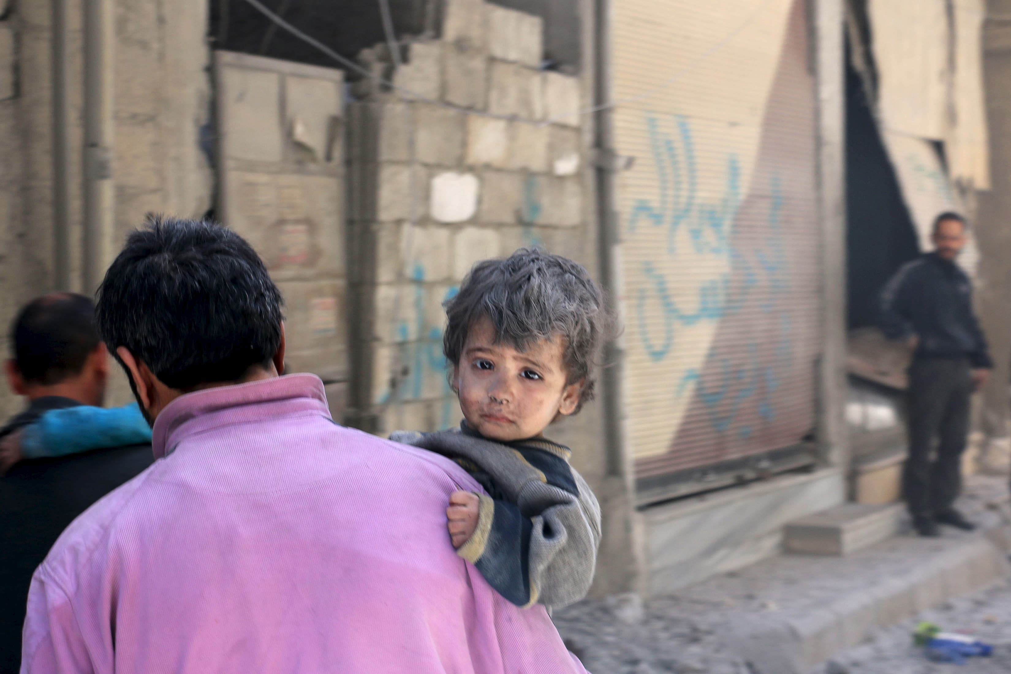A man carries a child who survived after he was pulled from under rubble following what activists said was shelling by forces loyal to Syria's President Bashar al-Assad at Ain Tarma in eastern Ghouta, a suburb of Damascus, Syria April 26, 2015.