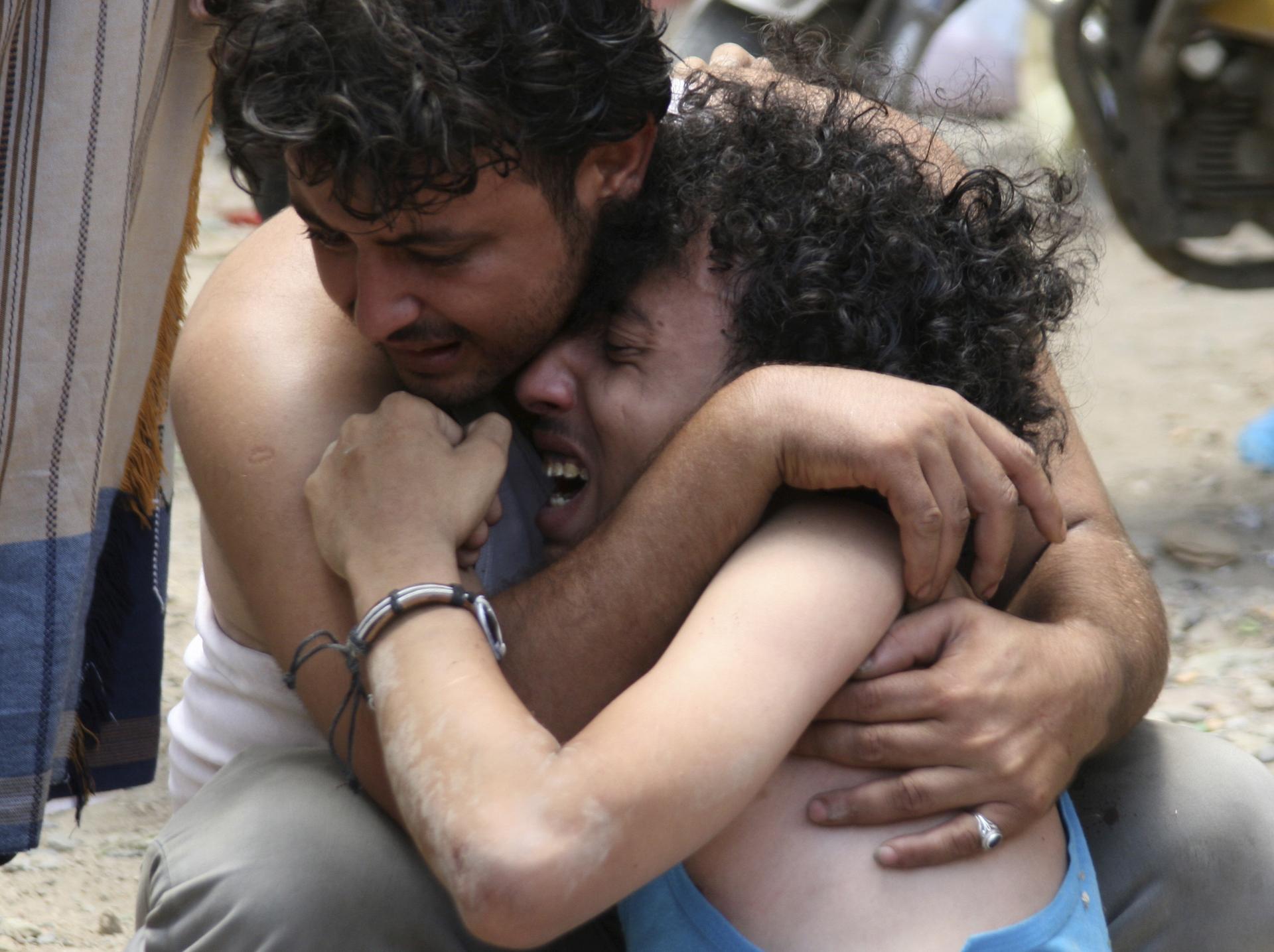 A man comforts another, whose brother was killed by a mortar shell blast during clashes