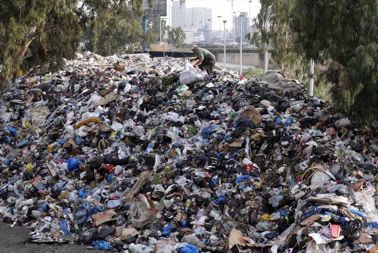 A scavenger sifts through garbage piled on the bank of Beirut river, Lebanon, on Aug. 24, 2015.