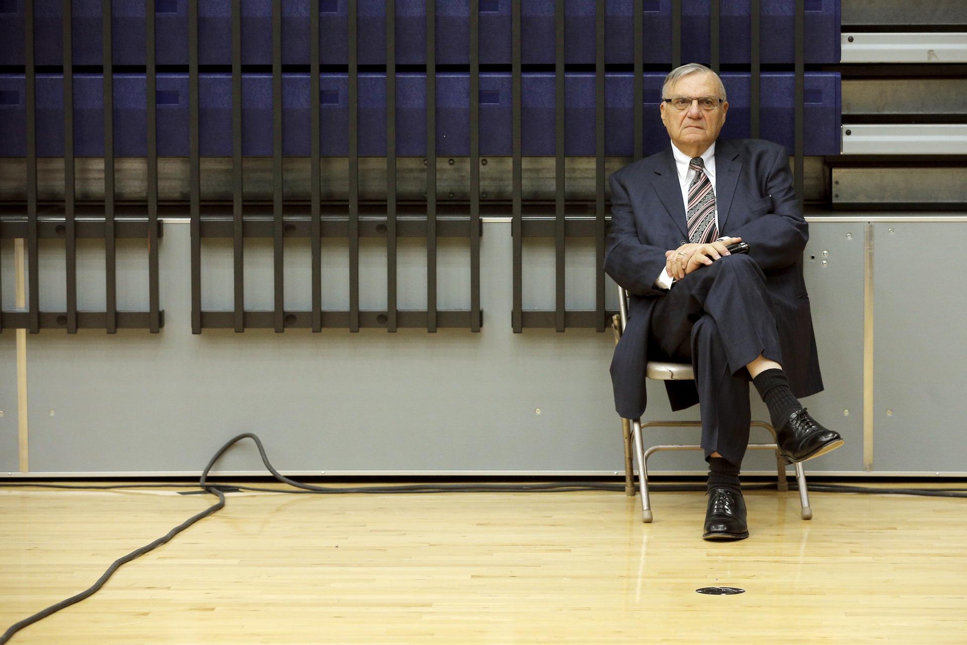 Arpaio sits on a folding chair in a gym