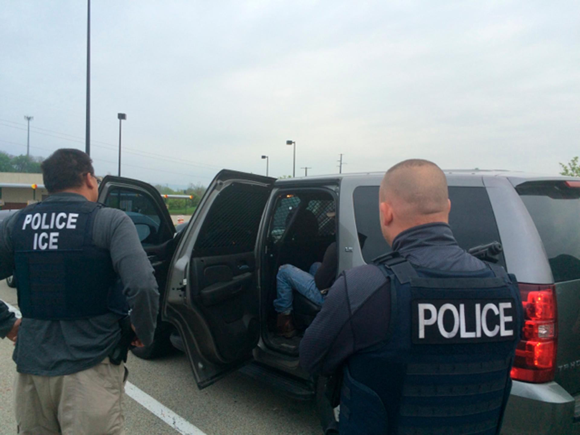 Agents with vests placing a man in car